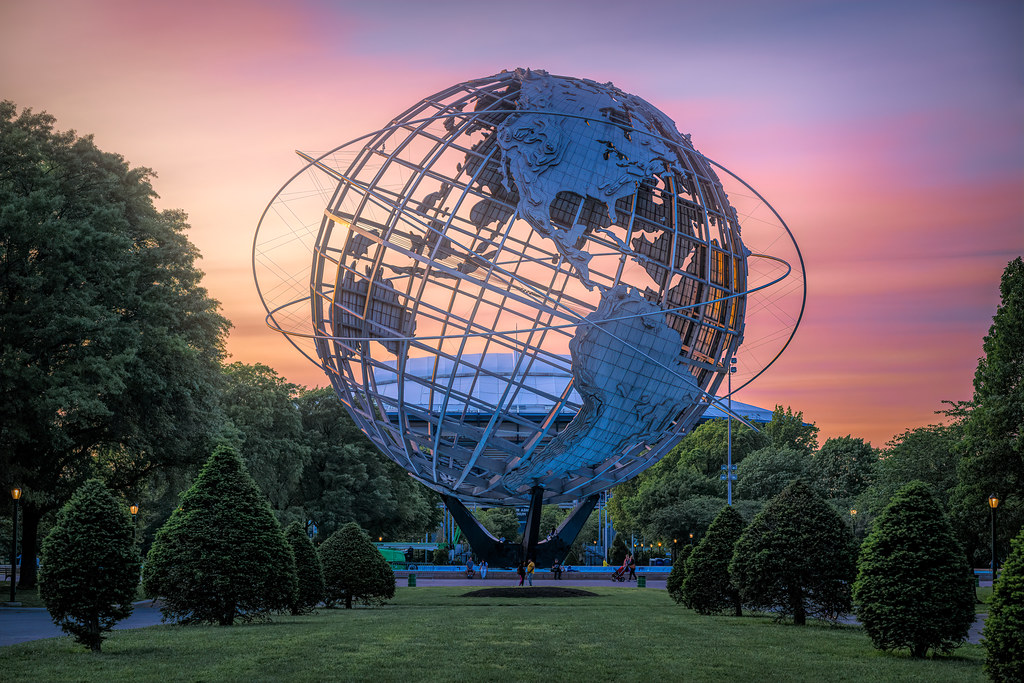 The Unisphere in Flushing Meadows, a top landmark for things to do in Rego Park after getting high, surrounded by trees and blue sky